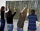 Schüler und Schülerinnen schreiben RELIGION an eine Tafel